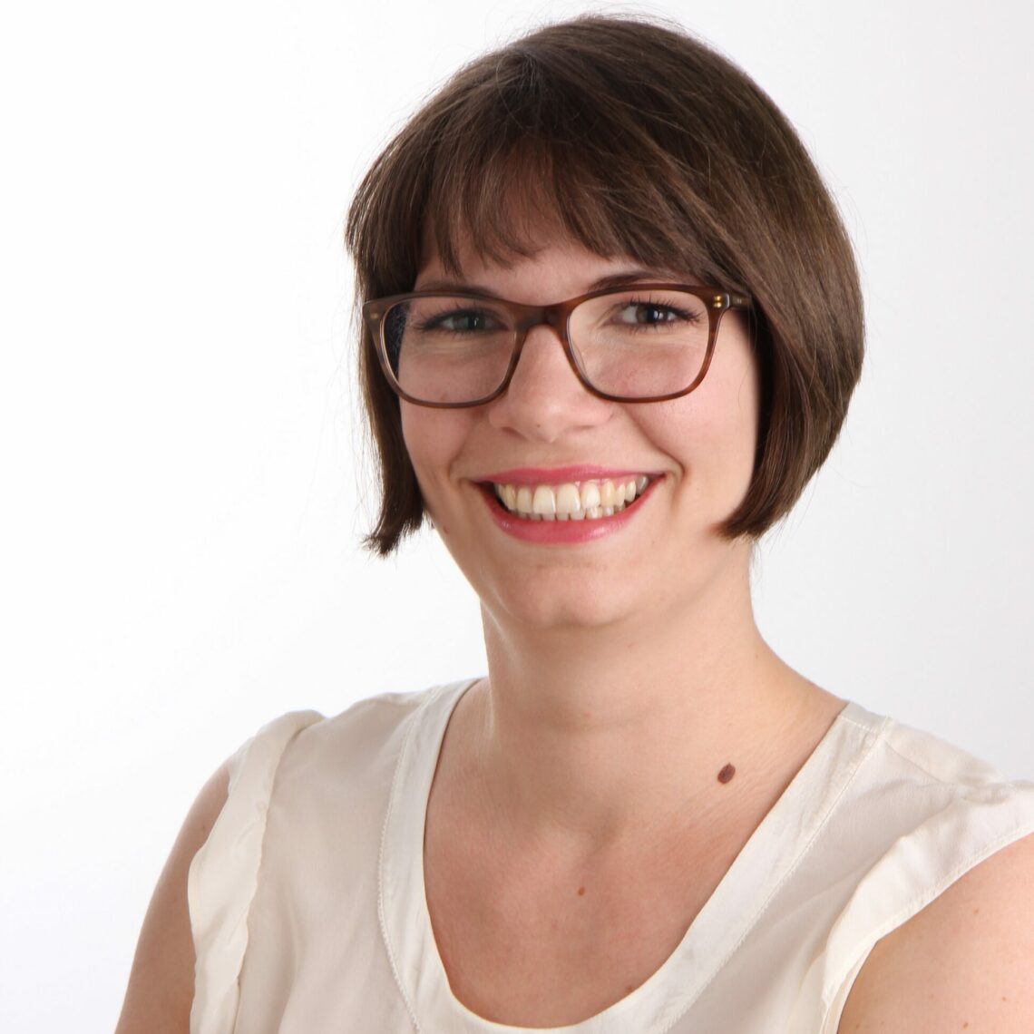 A woman wearing glasses and smiling at the camera